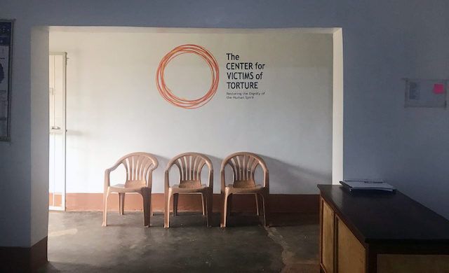 Gulu front office with CVT logo displayed on the wall with three chairs below.