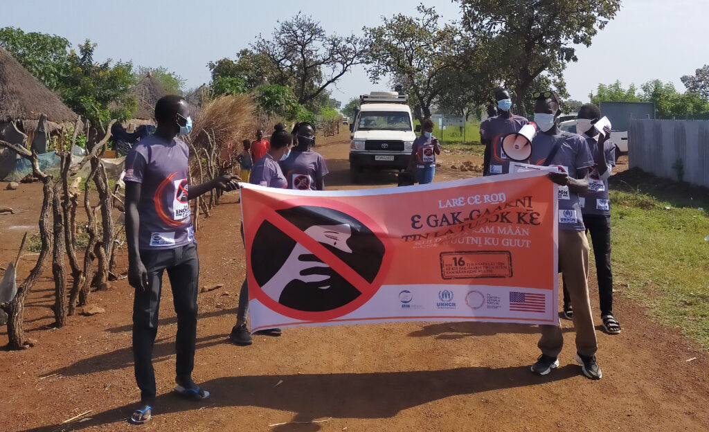 Gambella individuals hold a save life banner while on a road.