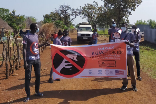Gambella individuals hold a save life banner while on a road.