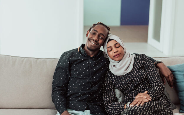 A couple cuddling on a couch.
