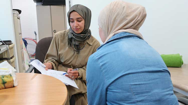 Two women discuss a document in an office setting.