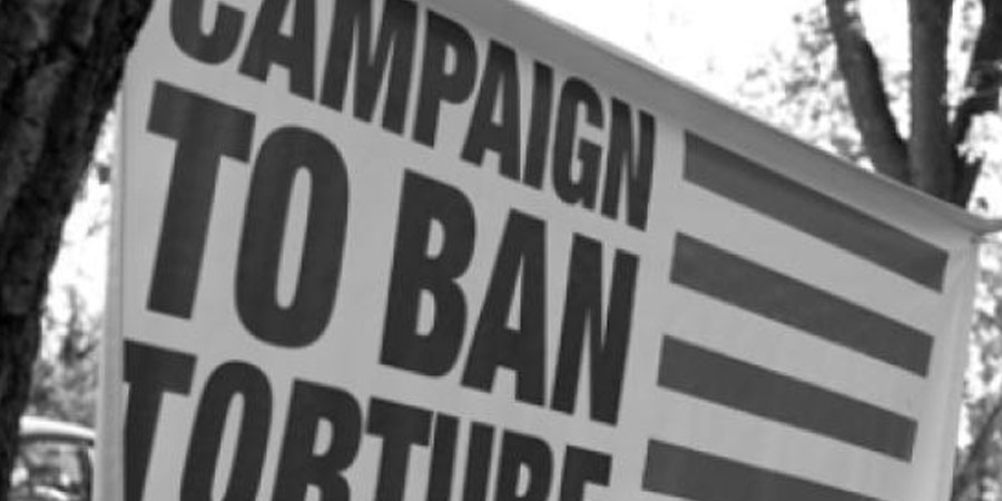 A black and white photo of a banner, which states: "Campaign To Ban Torture"